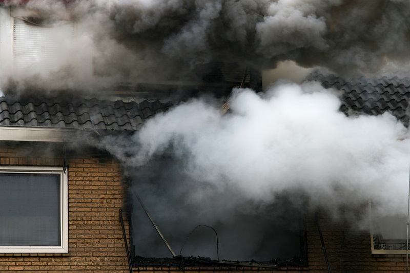 opary dymu wydobywające się z wnętrza domu